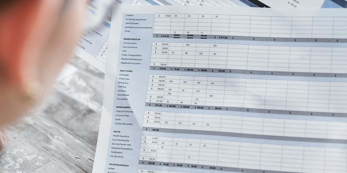 An individual diligently reviewing financial documents and calculations, emphasizing the careful budgeting required for real estate licensing fees and hidden costs.