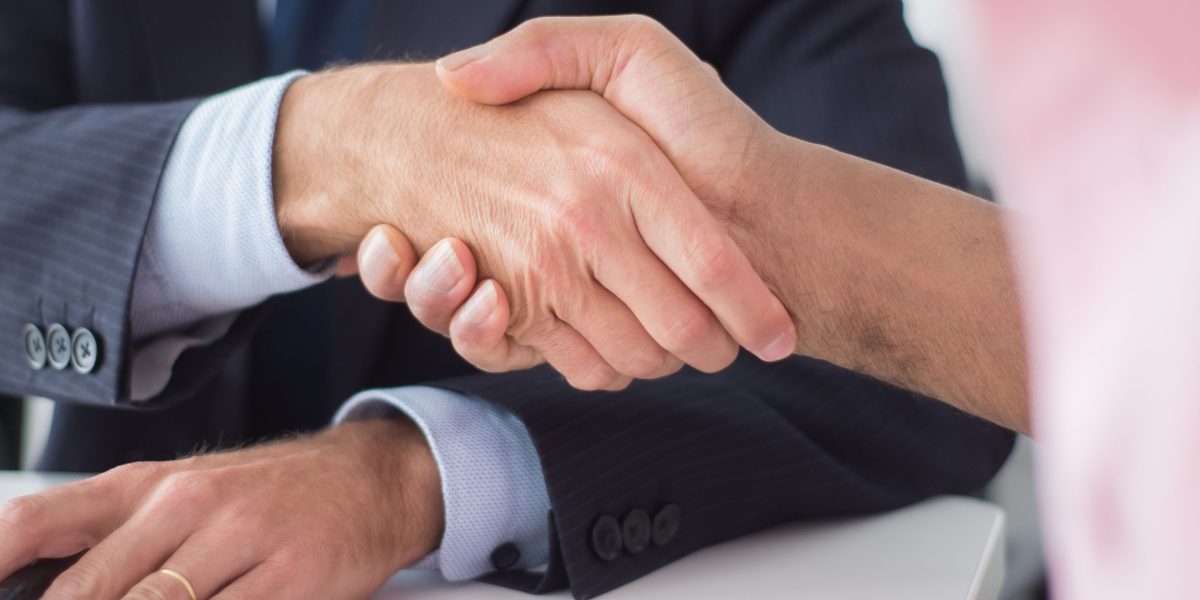 Two professionals shaking hands, signifying a successfully finalized property deal.