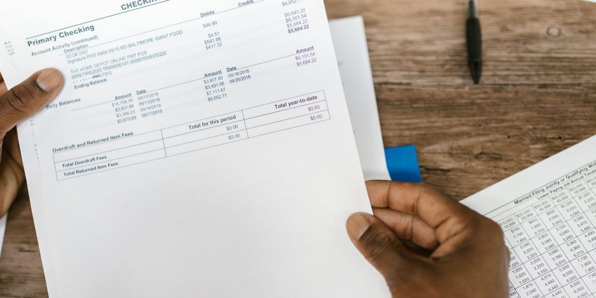A person carefully examining financial statements to plan a budget for accommodation expenses.
