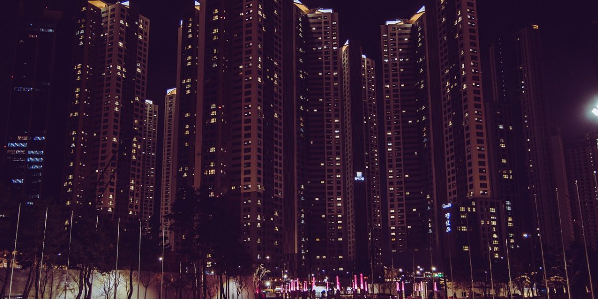 A person gazes out over a modern city skyline at sunrise, reflecting on aspirations of luxury living in a vibrant city.