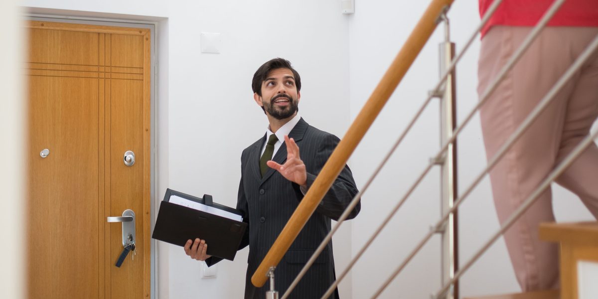 A real estate agent showing a property to a couple, pointing out features, symbolizing client interaction and viewings.