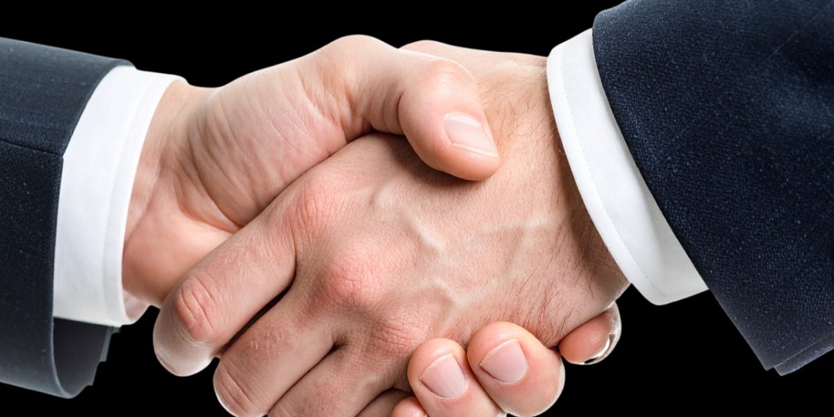 Two professionals shaking hands in a modern setting, representing a successful real estate transaction facilitated by a reputable agency.
