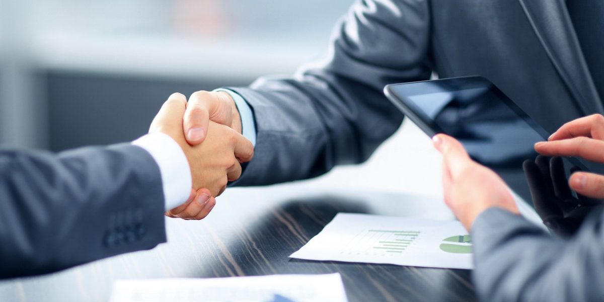 A professional discussion taking place around a table, with participants reviewing documents, reflecting the process of evaluating an agent's track record.