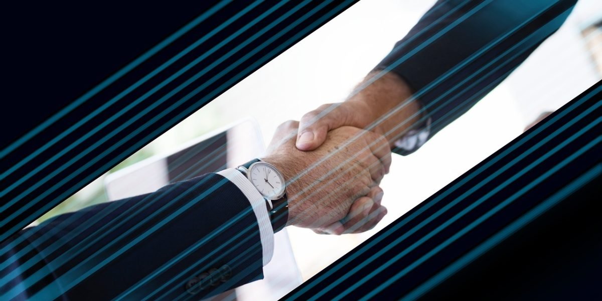 Two business people shaking hands across a desk, symbolizing a successful negotiation and agreement on terms.