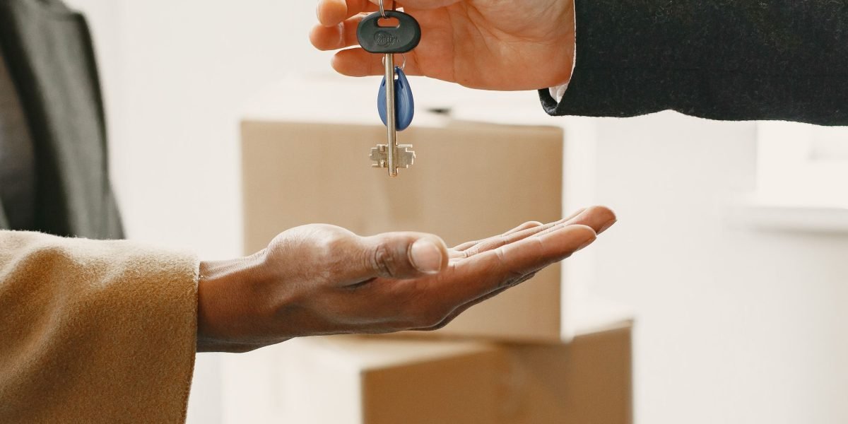 A cheerful couple receiving keys to their new home from a real estate agent, marking the successful completion of a property deal.